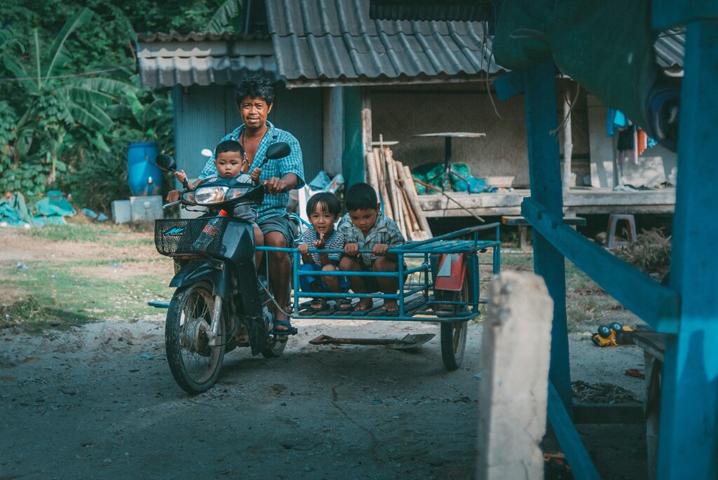 man with three children on saleng scooter in thailand