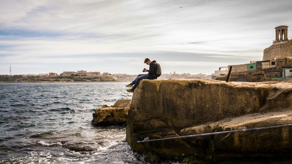 man sitting on a cliff in Malta, malta digital nomad visa