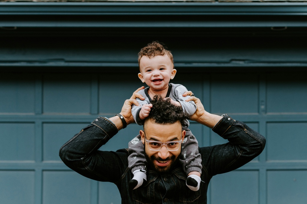 Man holding his little son on his shoulders, digital nomad family