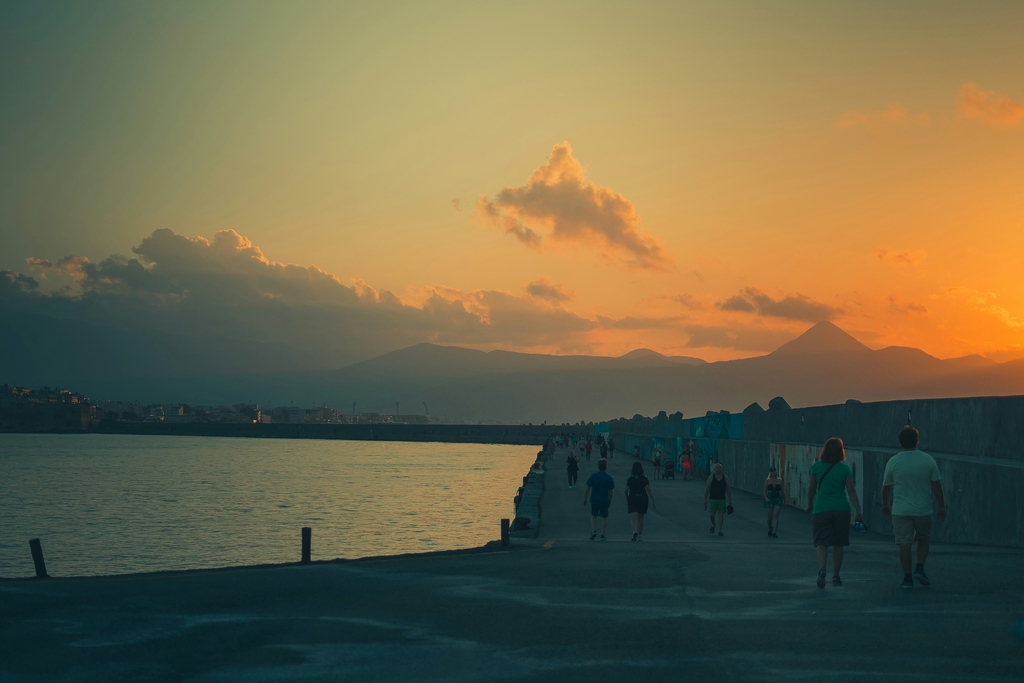 People walking on a promenade during sunset