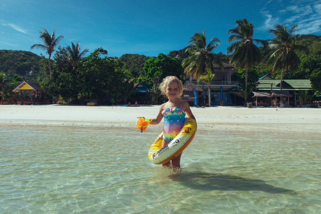 Little girl standing in the blue water of a beautiful tropical beach.