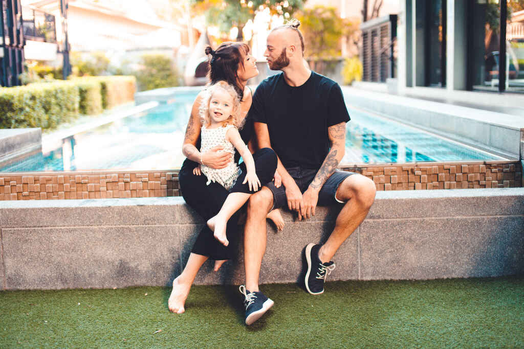 Family of three sitting at the edge of a pool, living in thailand with kids