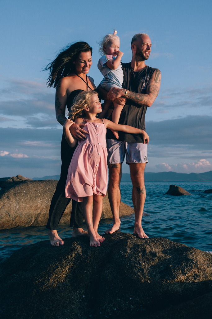 Family of four standing on a rock in the sea, living in Thailand with kids