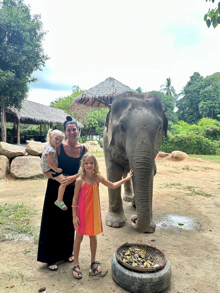 Mum with two young girls standing next to an elephant.