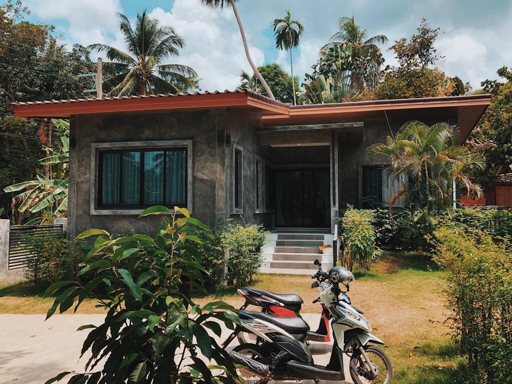 Gray house with orange roof in tropical surrounding