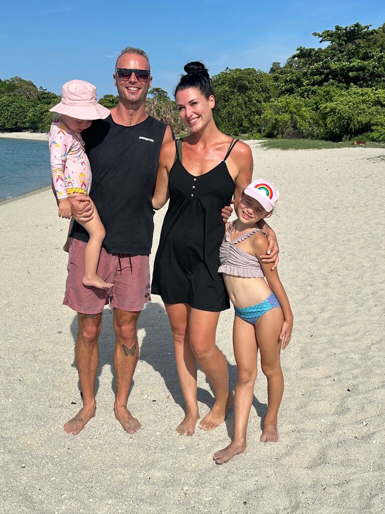 Family of 4 standing on an empty beach