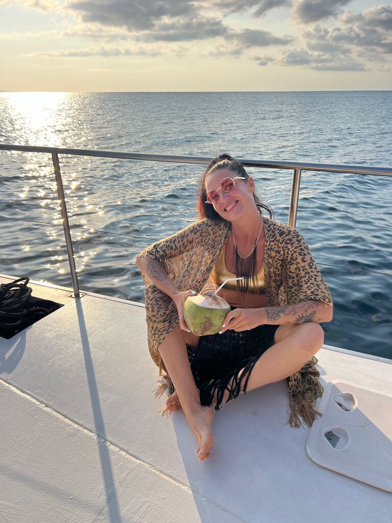 Woman with a coconut sitting on a catamaran.