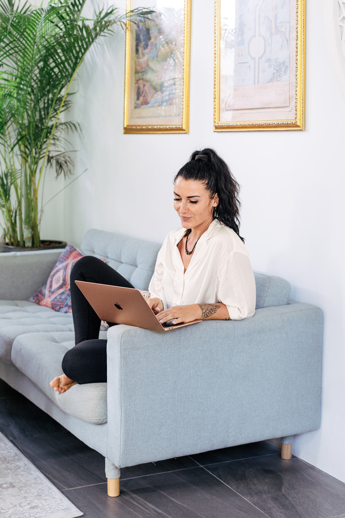 Woman sitting on a grey sofa with her laptop