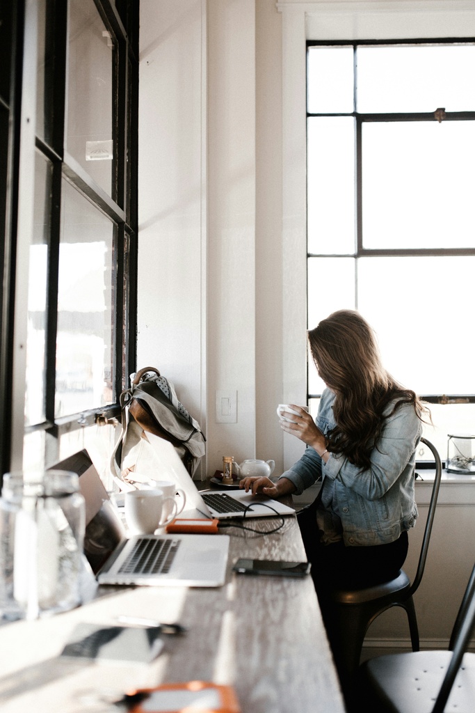 Woman sitting on a desk, working on a laptop