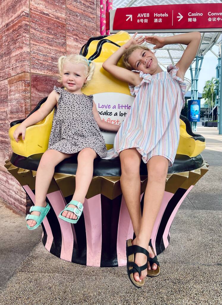 Two girls sitting on a cupcake figure