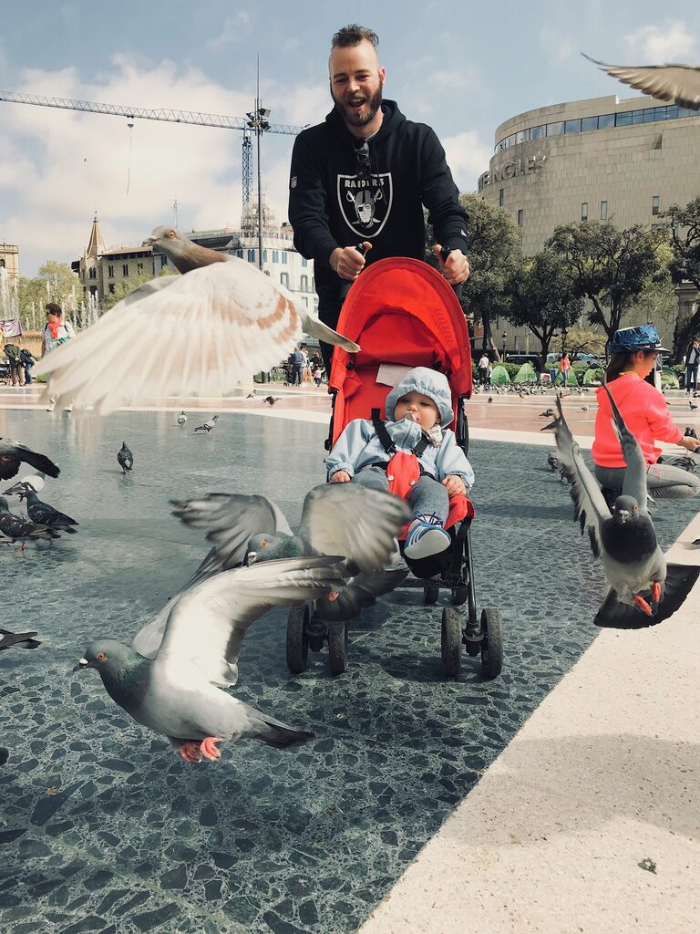 Dad pushing a red stroller with giggling toddler