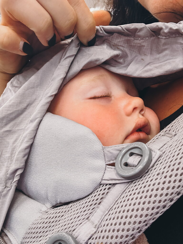 Baby sleeping in baby carrier, an essential on the toddler travel checklist