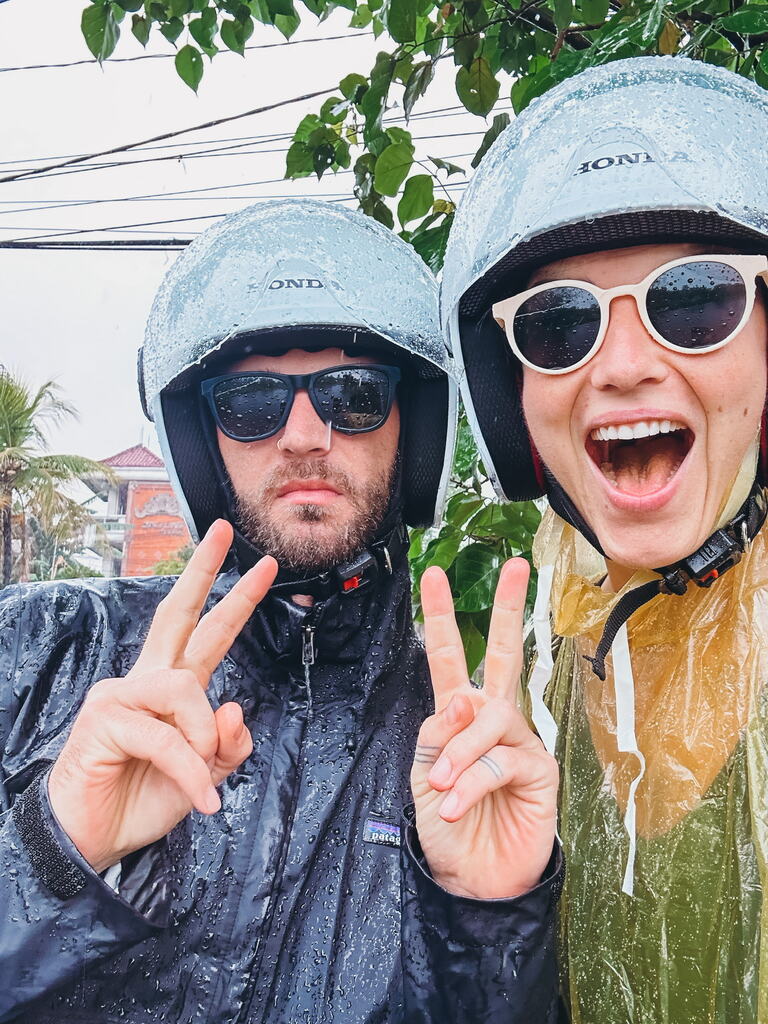 A yound couple with scooter helmets in the rain