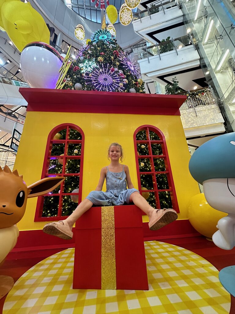 Girl sitting on a giant gift in a Thai mall