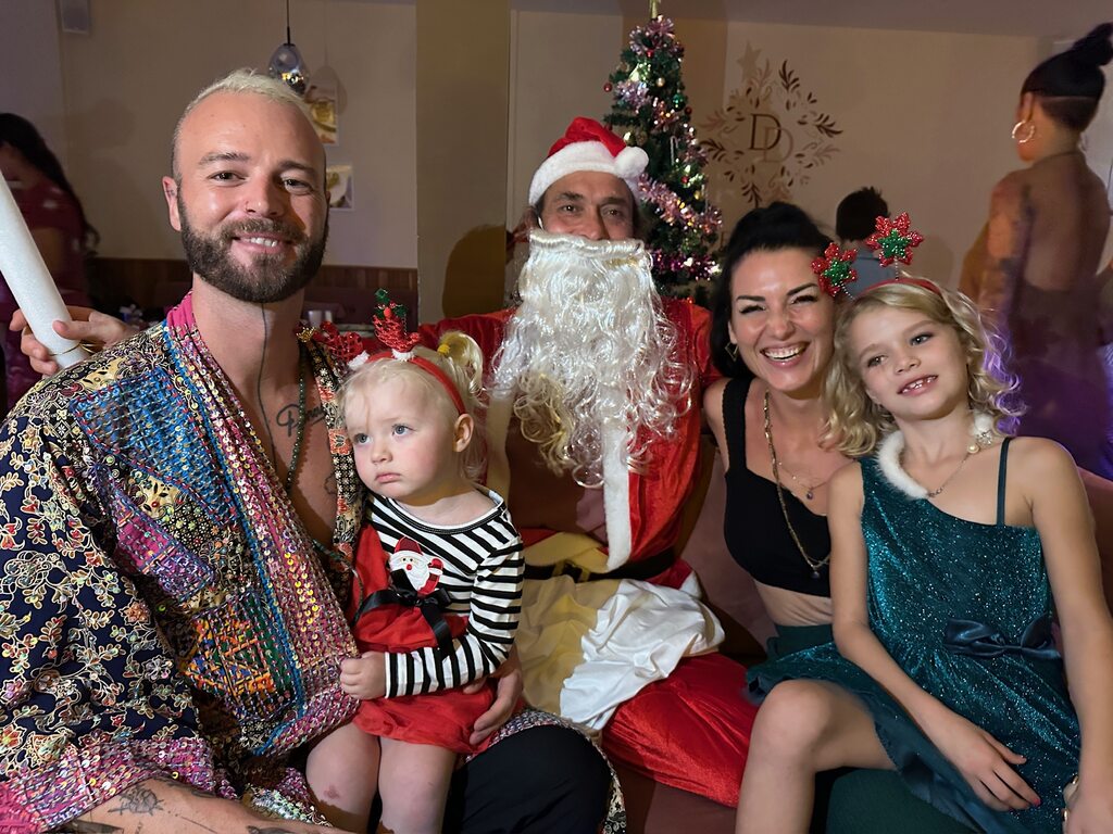 Family of four sitting next to Santa Claus, Christmas in Thailand