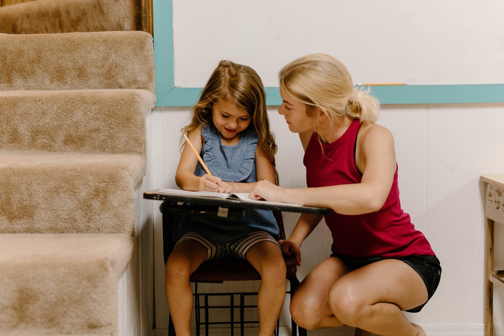 Woman helps a young girl with homework