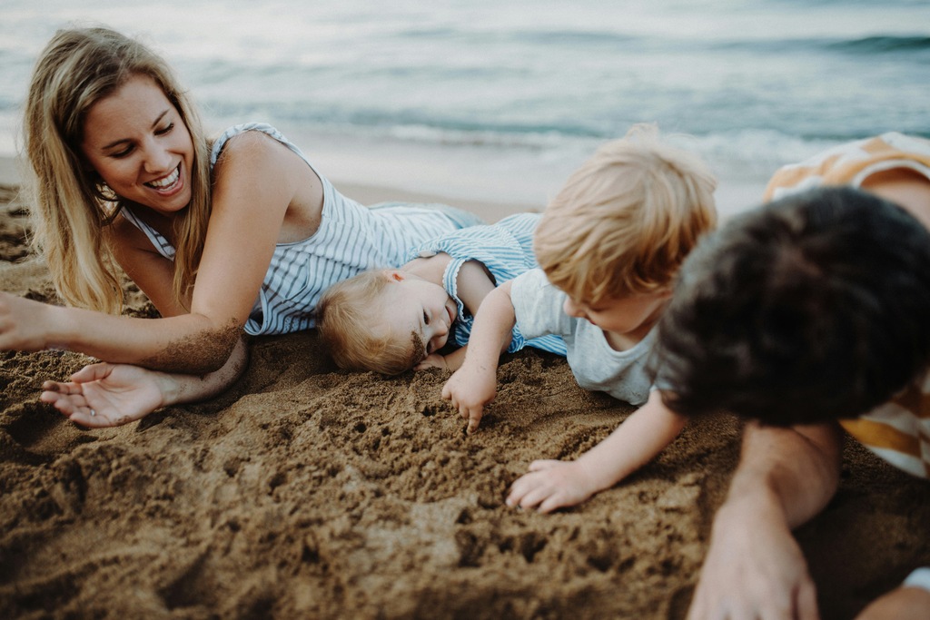 Mum with 3 kids playing in the sand