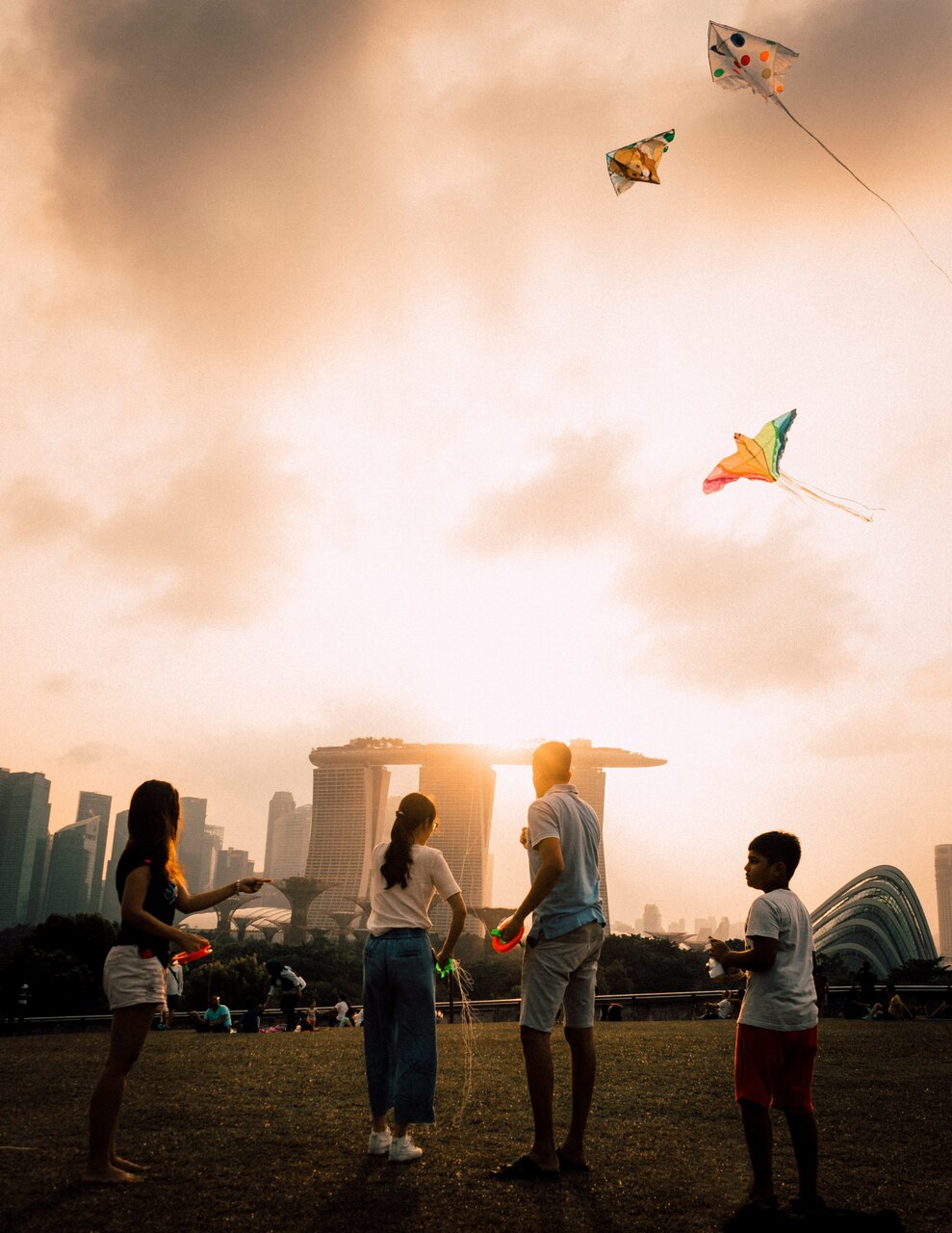 Family playing with a kite in fron of Singapore skyline.