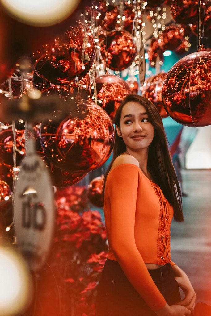 Young Thai woman poses in front of red christmas decoration