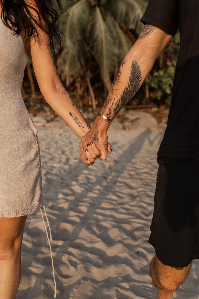 Couple holding hands on the beach. Digital Nomad Parents