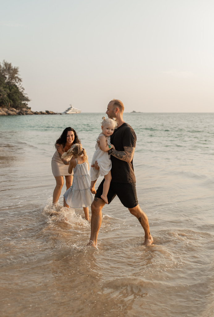 Family of four playing in the shallow water of a tropical beach.