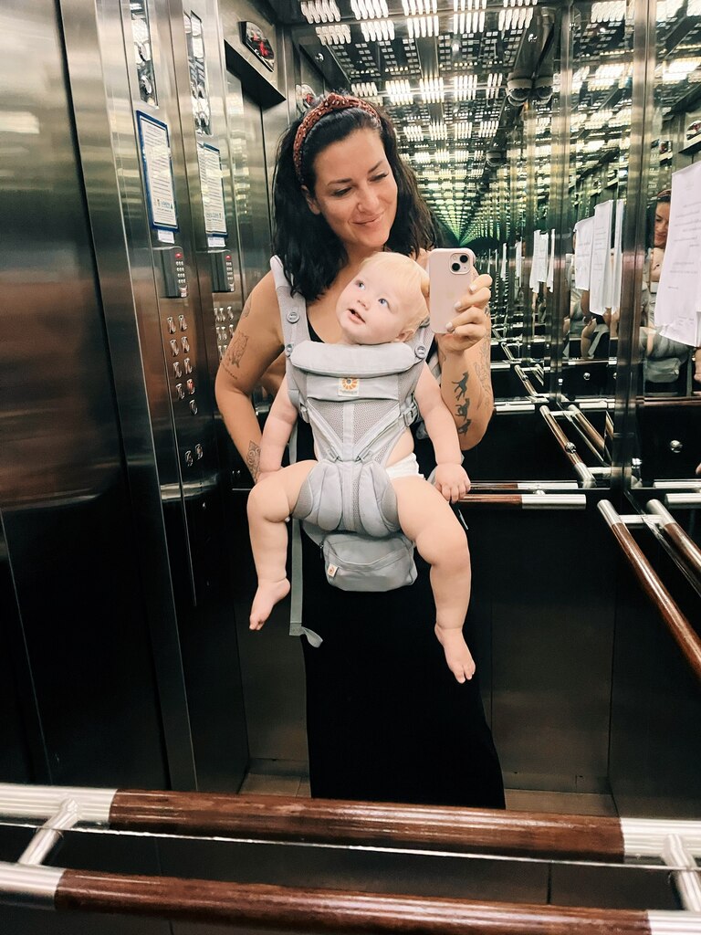 Mum in an elevator with young baby in the carrier