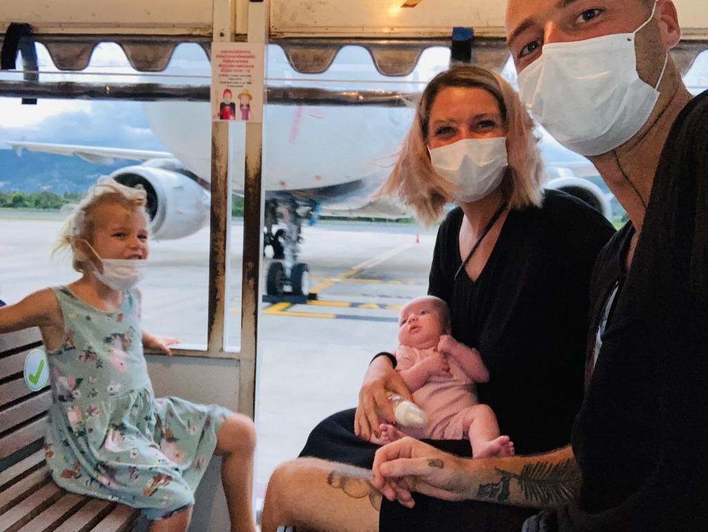 Family of four with a newborn sitting in an airport mini bus on their way to the plane