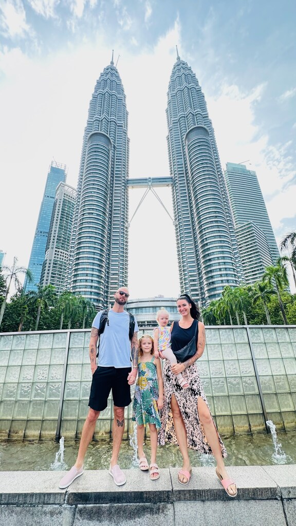 Family of four posing in front of twin towers in KL