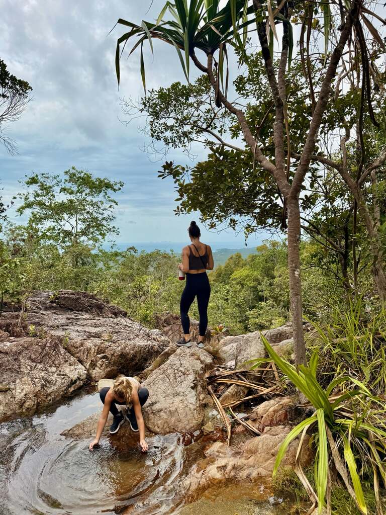 Woman standing in a jungle on a waterfall cliff.