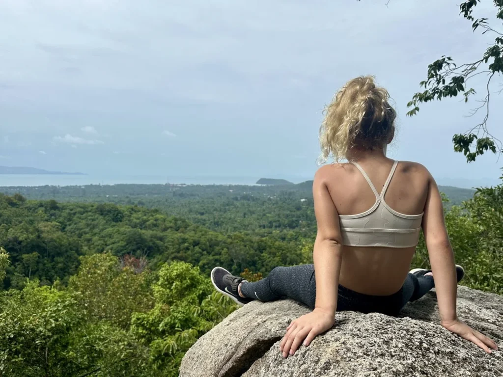 Girl sitting on a rock looking at the panoramic view of a palm tree valley