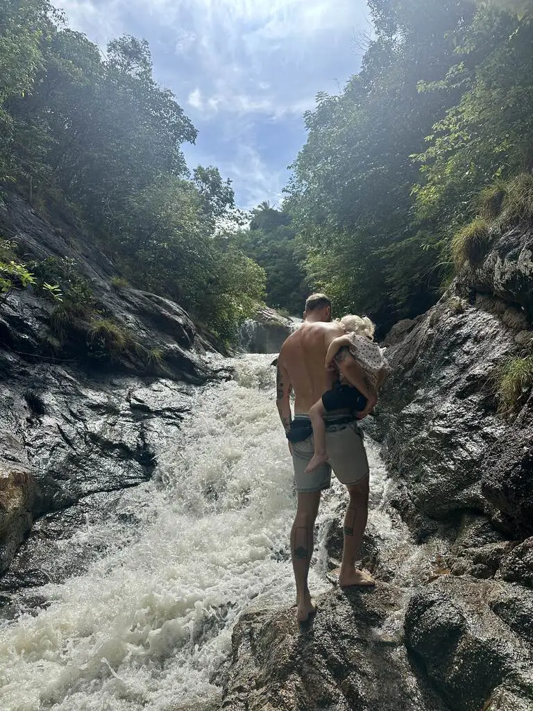 Dad carrying his little daughter at a waterfall.