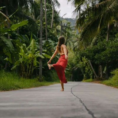 Woman in red dress dancing on a street with palm trees