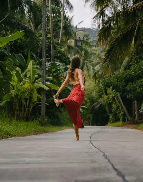 Woman in red dress dancing on a street with palm trees