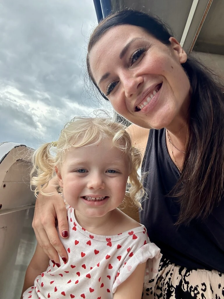 Mum and daughter posing for selfie at airport, traveling with toddler