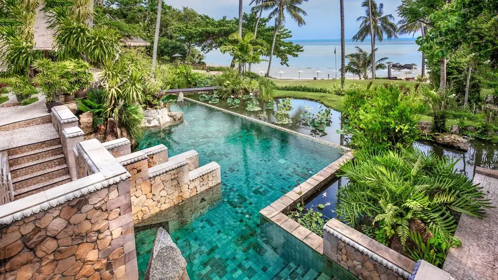 Hotel Pool with Palm trees and seaview in the background