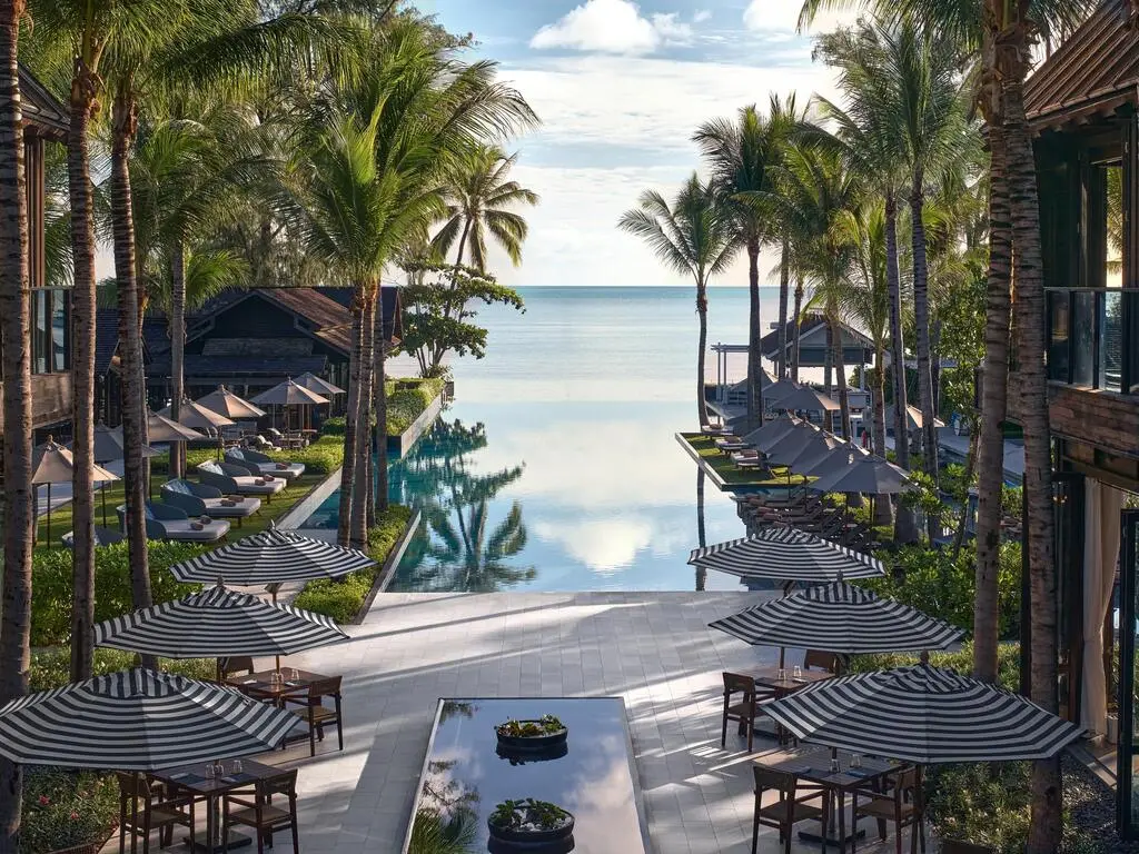 Hotel pool area with palm trees and infinity pool towards the sea