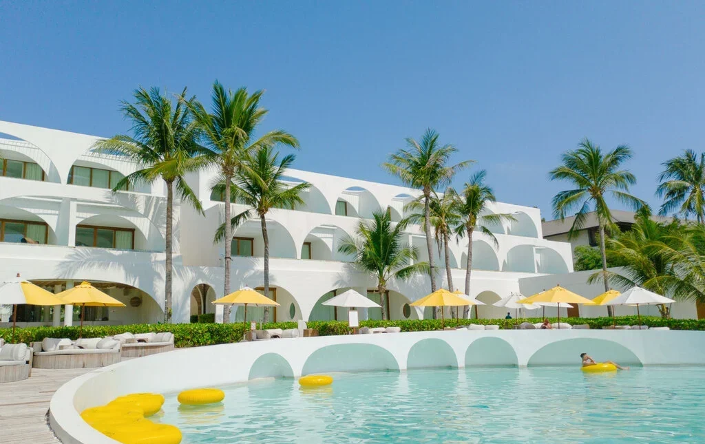 Bright Hotel Pool with white buildings and coconut trees in the background