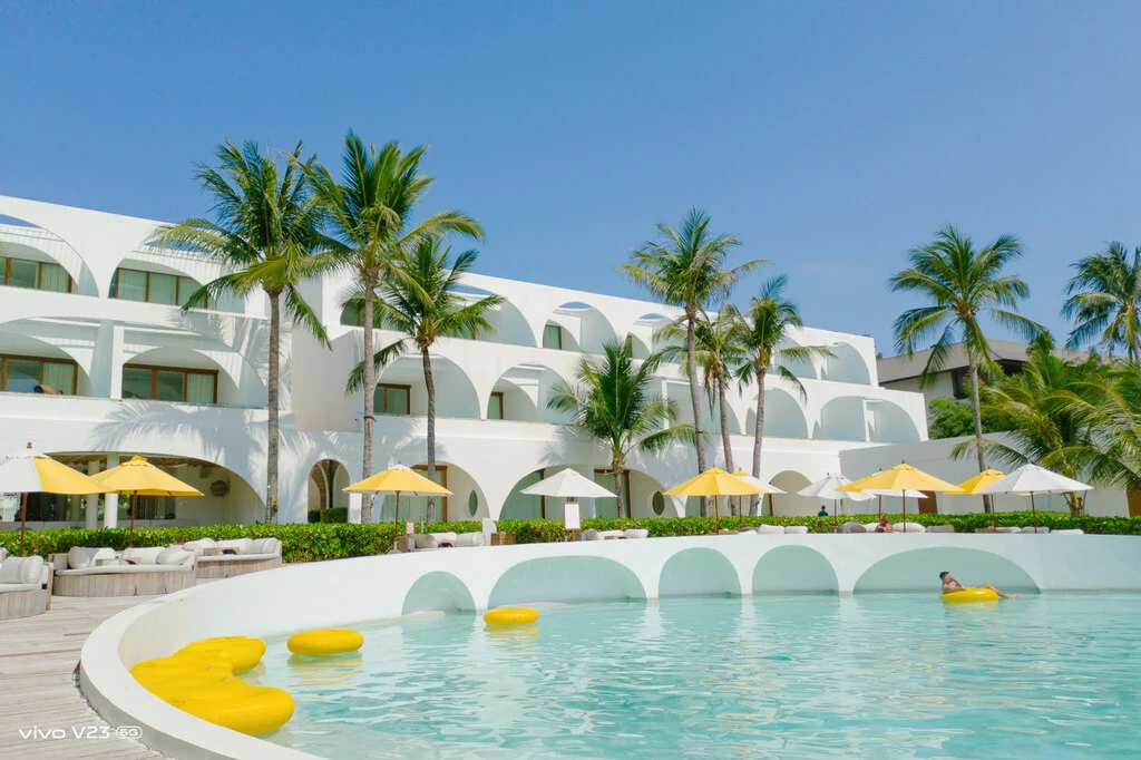 Bright Hotel Pool with white buildings and coconut trees in the background