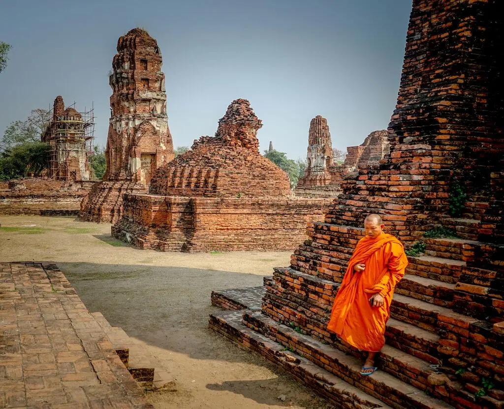 Thai monk in orange robe in a religious site.