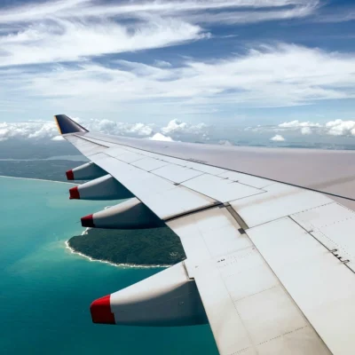 Airplane Wing flying over ocean, best airlines to fly to Thailand.