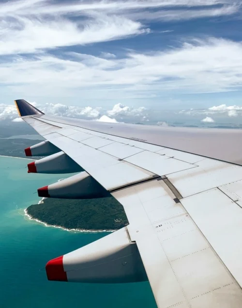 Airplane Wing flying over ocean, best airlines to fly to Thailand.