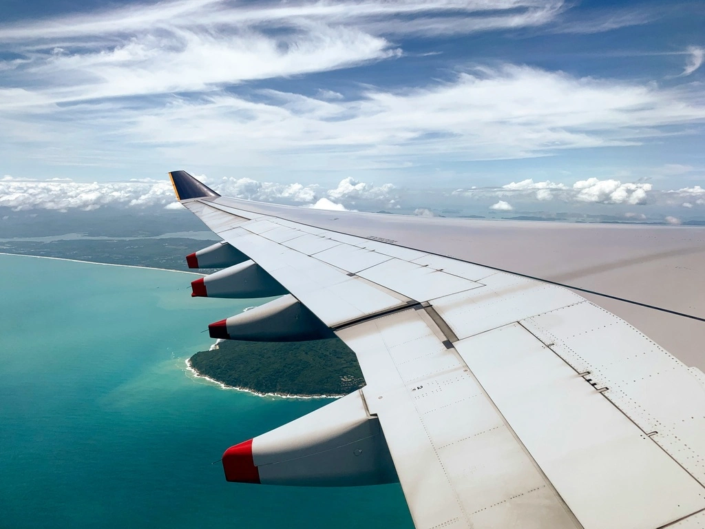 Airplane Wing flying over ocean, best airlines to fly to Thailand.