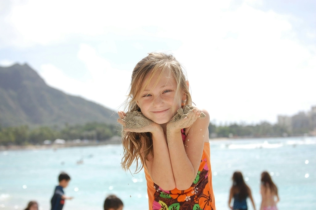 Blond girl playing with sand on the beach