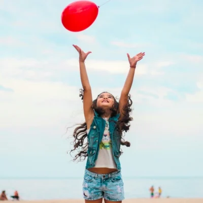 Girl playing on the beach with a red balloon, 50 Must-Try Beach Activities for Kids That Will Inspire You