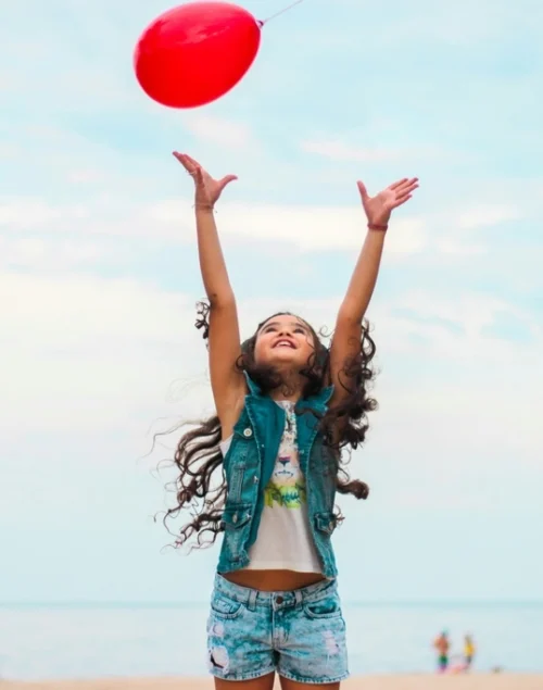 Girl playing on the beach with a red balloon, 50 Must-Try Beach Activities for Kids That Will Inspire You