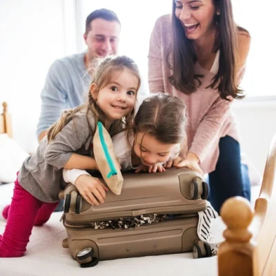 Family of four trying to close a big suitcase.