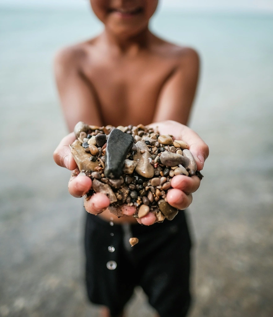 Boy holding pebbles in his hands, best beach activities for kids