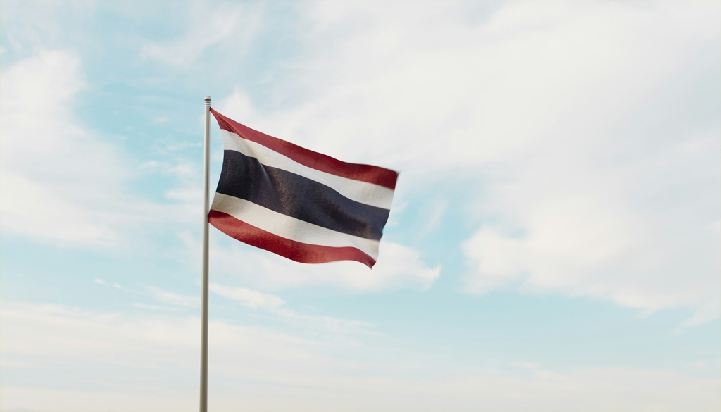 Thailands national flag in front of a blue sky.