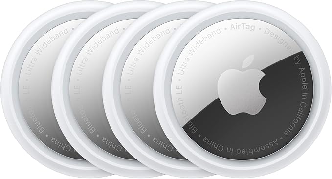 Four white and silver apple airtags laying next to each other.
