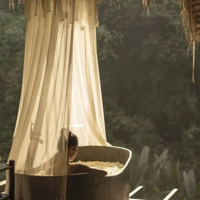 Woman sitting in an outdoor bathtub with jungle view